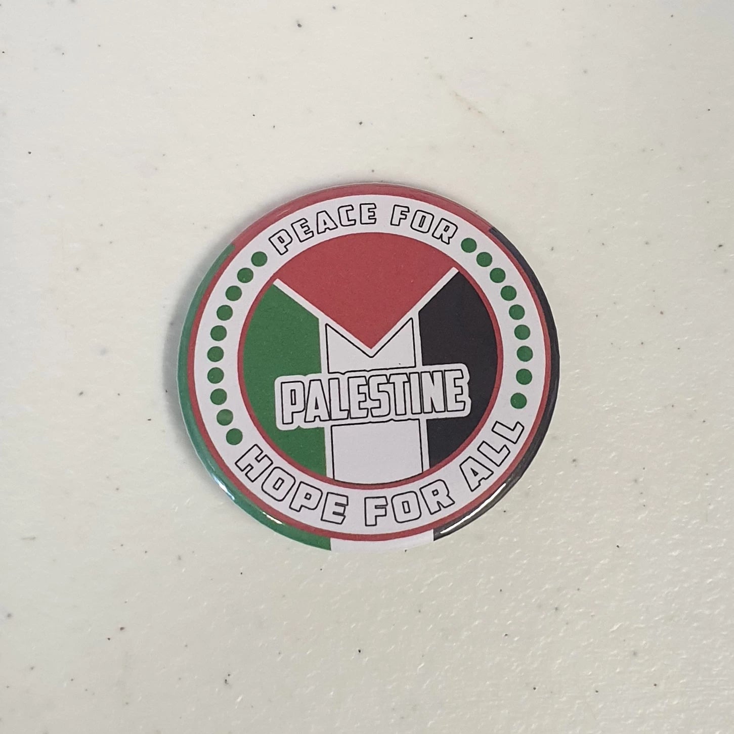 Button badge with 'Peace for Palestine, Hope for All' text and flag design on a white background
